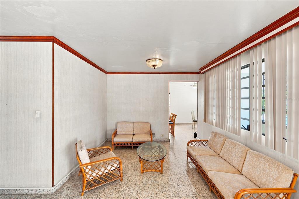 A living room with rattan furniture, a glass coffee table, and vertical window blinds — 16 CALLE EDUARDO QUEVEDO, ISABELA, PR