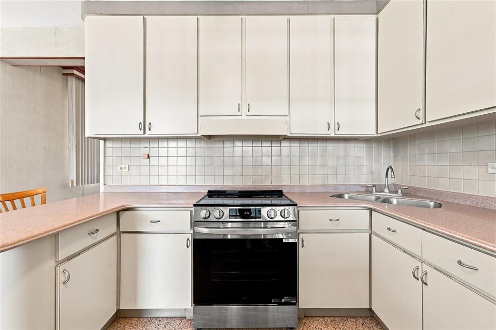 A kitchen features white cabinets, a stainless steel stove, and pink laminate countertops — 16 CALLE EDUARDO QUEVEDO, ISABELA, PR