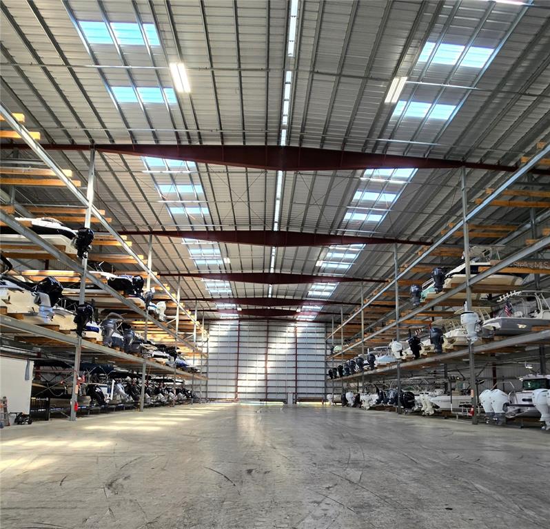 A large indoor boat storage facility with multi-level metal racks holding numerous motorboats — 10 RIO VISTA DRIVE, PALM COAST, FL