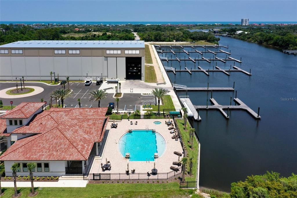 An aerial view shows a swimming pool, a large warehouse, and a boat slip marina — 10 RIO VISTA DRIVE, PALM COAST, FL