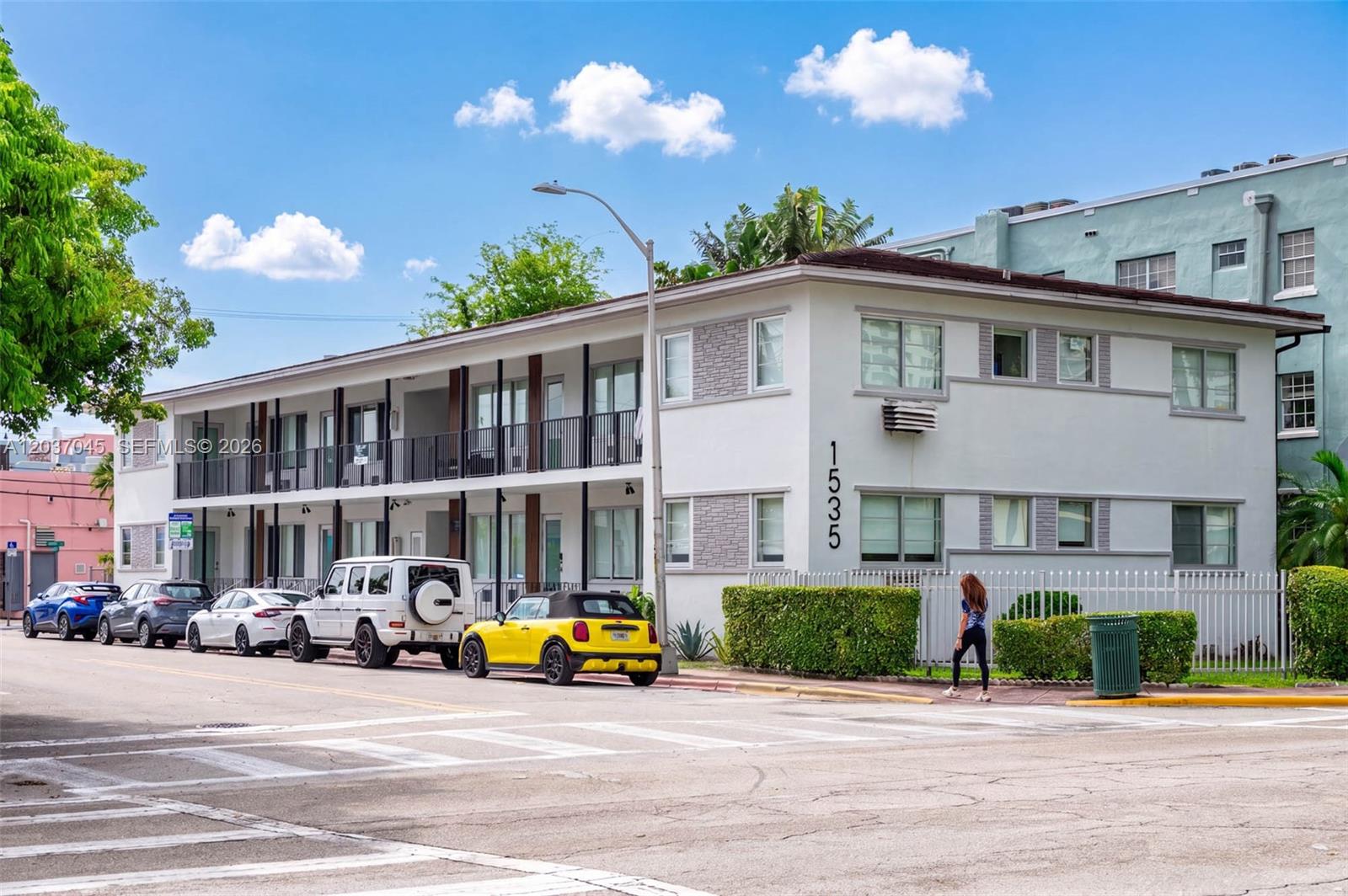 A two-story apartment building with a white exterior and a row of parked cars — MIAMI BEACH, FL