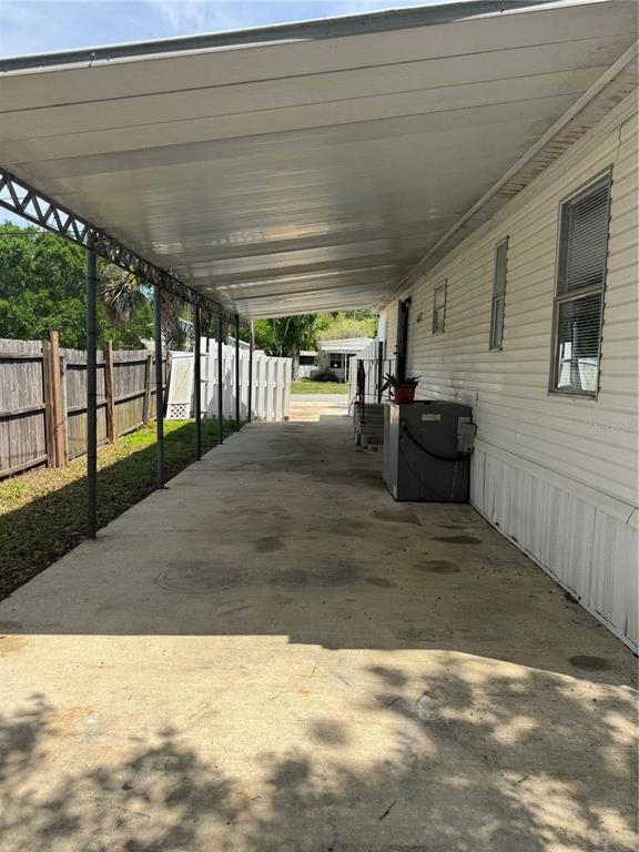 A concrete carport with a metal roof extends along the side of a mobile home — 5406 SYDNEY STREET, PORT ORANGE, FL