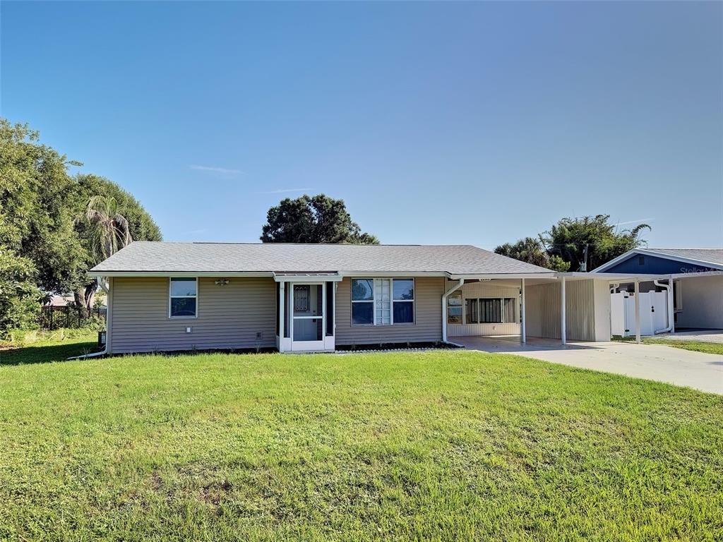 A single-story house with tan siding, a gray roof, and an attached carport — 22392 BUFFALO AVENUE, PORT CHARLOTTE, FL