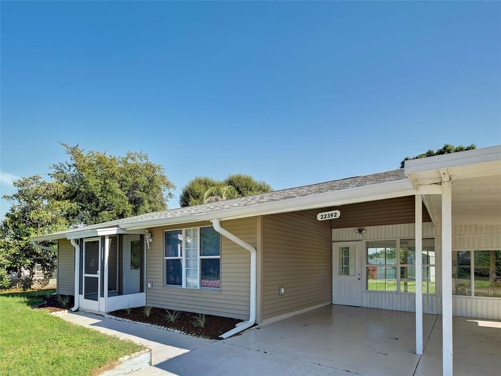 A single-story house with tan siding, a screened-in porch, and an attached carport — 22392 BUFFALO AVENUE, PORT CHARLOTTE, FL