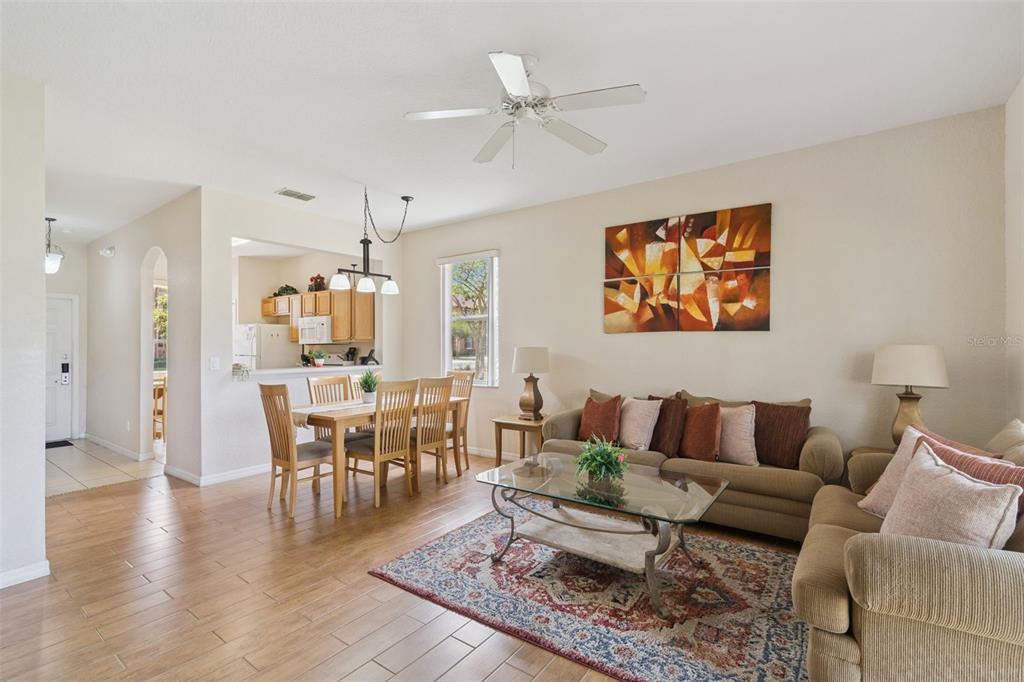 A living and dining area with wood-look tile floors, a ceiling fan, and neutral walls — 2205 CALABRIA AVENUE, DAVENPORT, FL