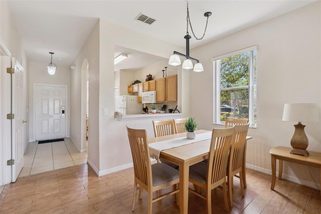 A dining area with a wooden table and chairs sits adjacent to an open kitchen — 2205 CALABRIA AVENUE, DAVENPORT, FL