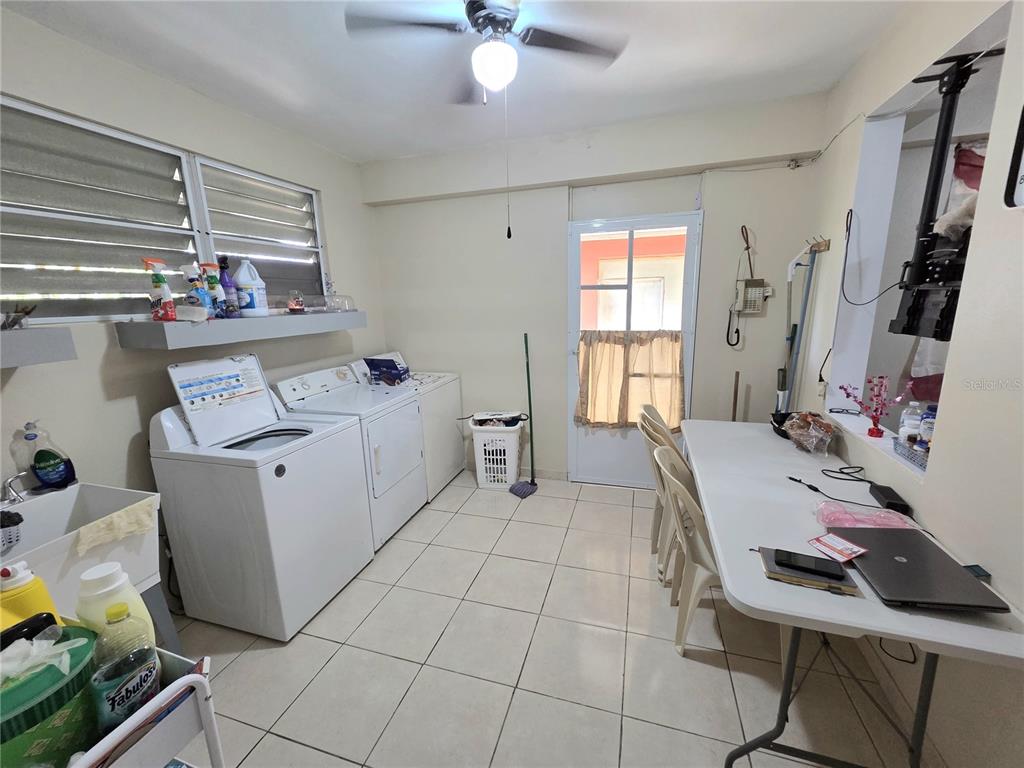 A laundry room features a washer, dryer, utility sink, and a folding table with chairs — 173 KM 15.8, CIDRA, PR