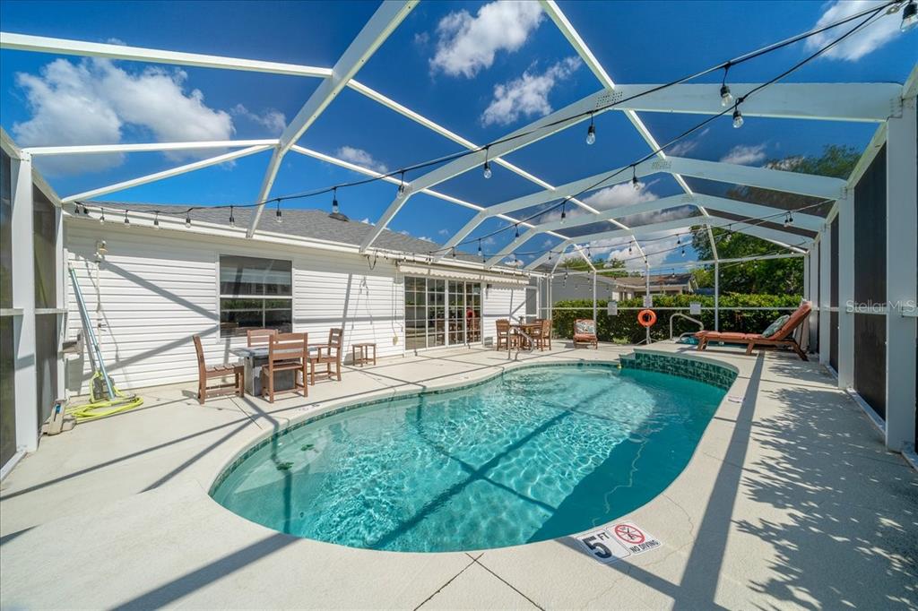 A single-story white house with a garage and a landscaped front yard at sunset — 987 CANDLER PLACE, THE VILLAGES, FL