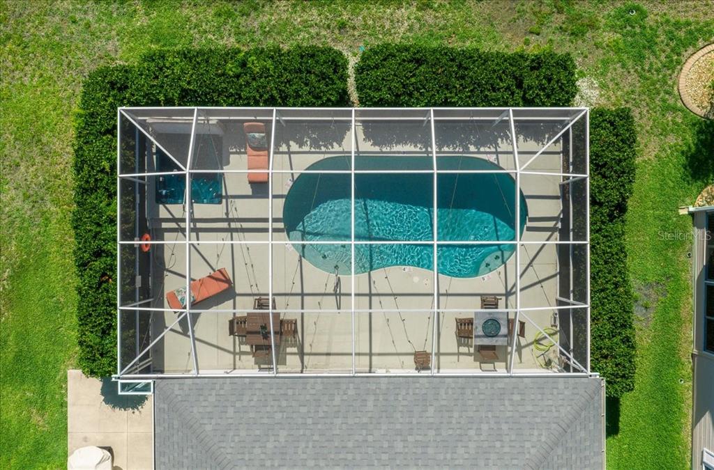 An aerial view of a backyard swimming pool enclosed by a screened-in lanai — 987 CANDLER PLACE, THE VILLAGES, FL