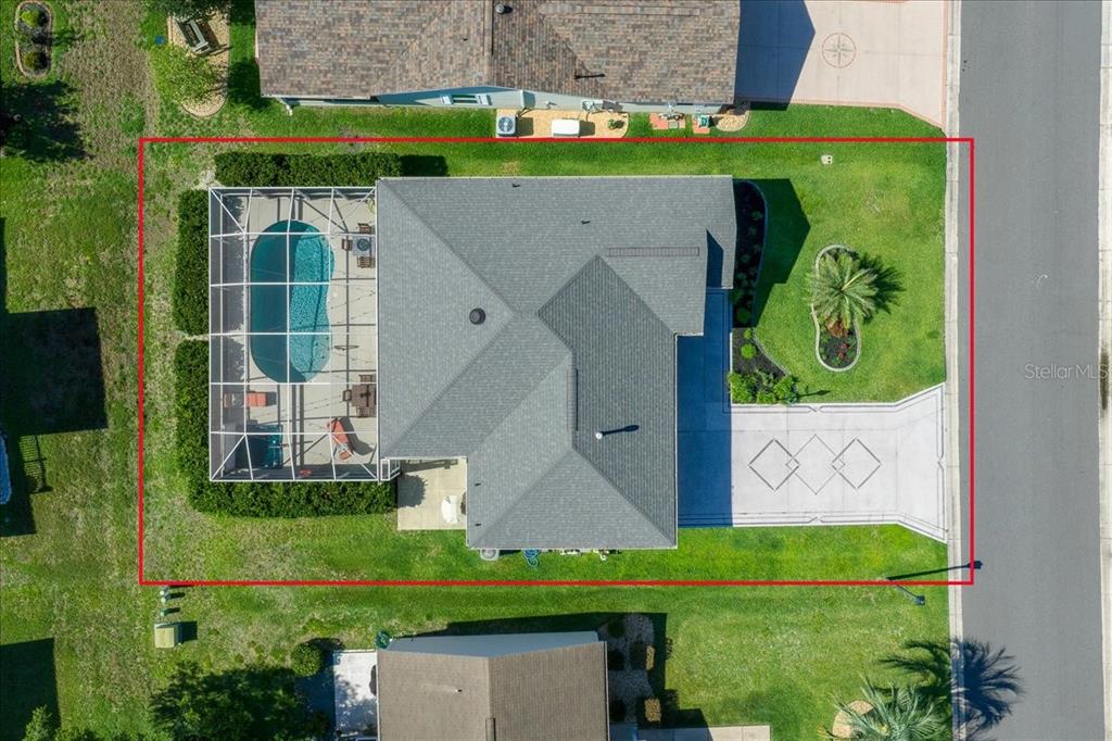 An aerial view shows a house with a screened-in pool and a paved driveway — 987 CANDLER PLACE, THE VILLAGES, FL