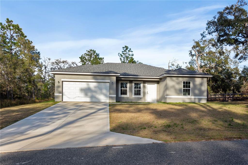 A single-story house with a gray stucco exterior, a two-car garage, and a concrete driveway — 1569 W MC NEAL DRIVE, CITRUS SPRINGS, FL