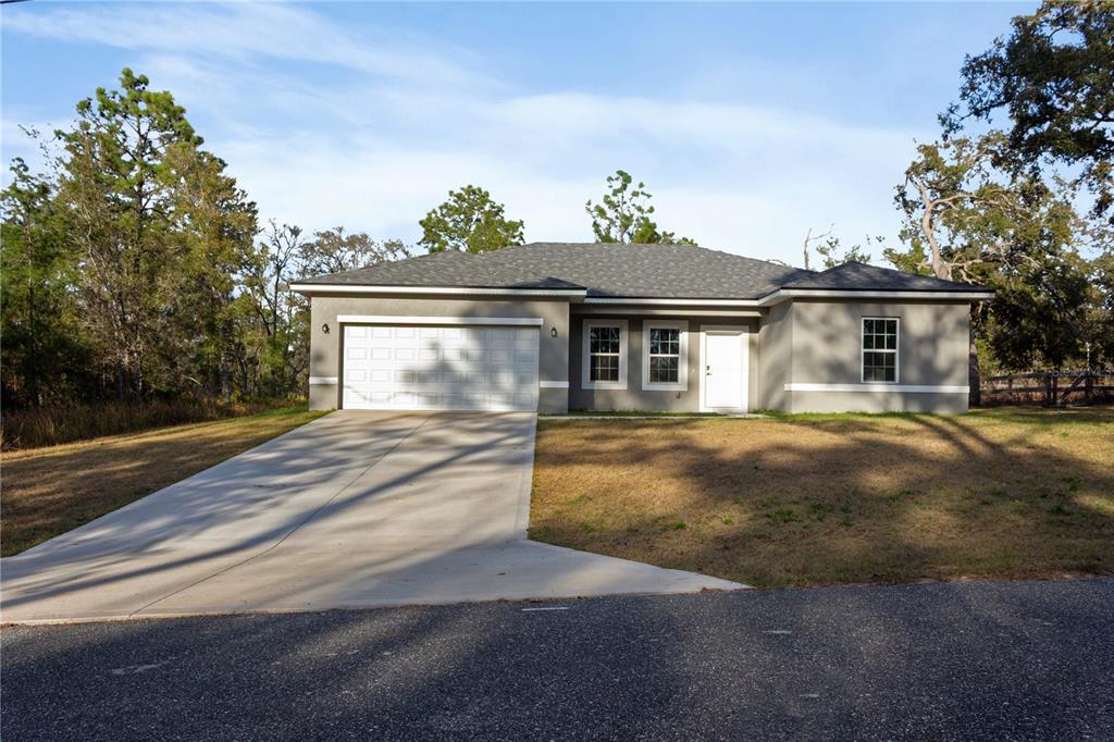 A single-story house with a gray stucco exterior, a two-car garage, and a concrete driveway — 1569 W MC NEAL DRIVE, CITRUS SPRINGS, FL