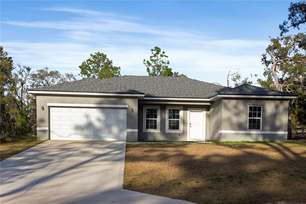 A single-story house with a gray stucco exterior, a two-car garage, and a concrete driveway — 1569 W MC NEAL DRIVE, CITRUS SPRINGS, FL