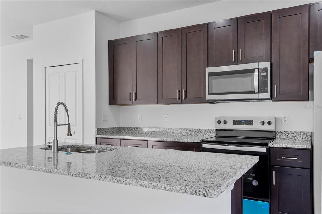 A kitchen features dark wood cabinets, granite countertops, a stainless steel microwave, and a kitchen island — 1569 W MC NEAL DRIVE, CITRUS SPRINGS, FL
