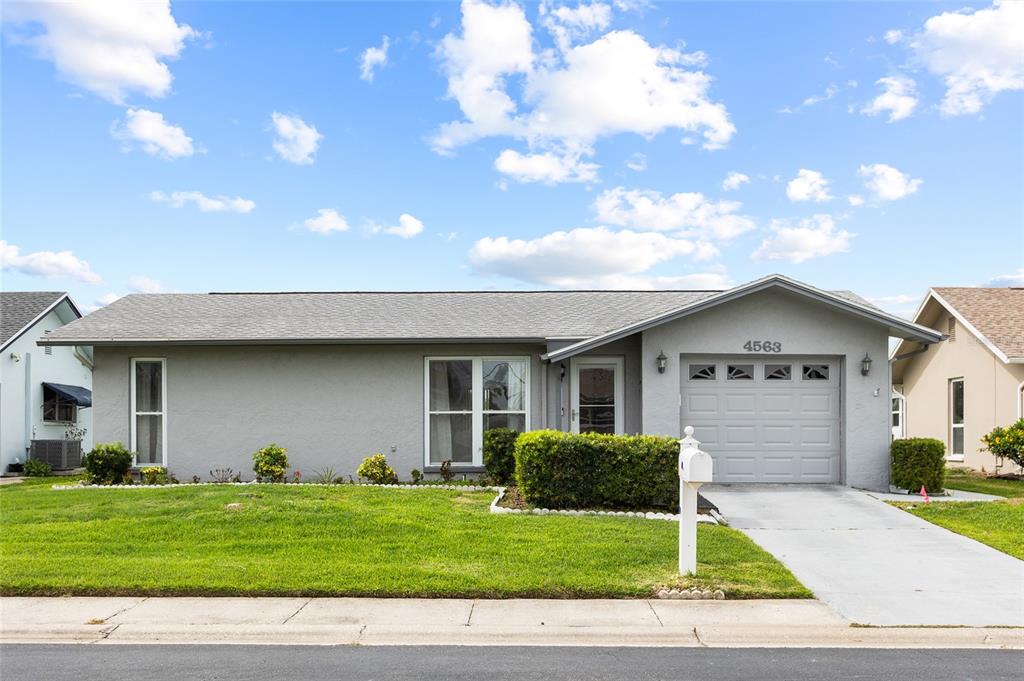 A single-story gray house with a front-facing garage, a lawn, and a concrete driveway — 4563 GREAT LAKES DRIVE S, CLEARWATER, FL