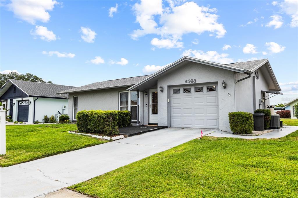 A single-story gray house with a garage and a front lawn under a blue sky — 4563 GREAT LAKES DRIVE S, CLEARWATER, FL