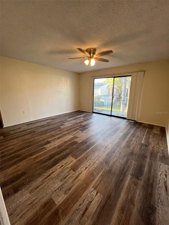 An empty room features wood-look flooring, a ceiling fan, and sliding glass doors — 6043 VILLAGE CIRCLE UNIT 6043, ORLANDO, FL