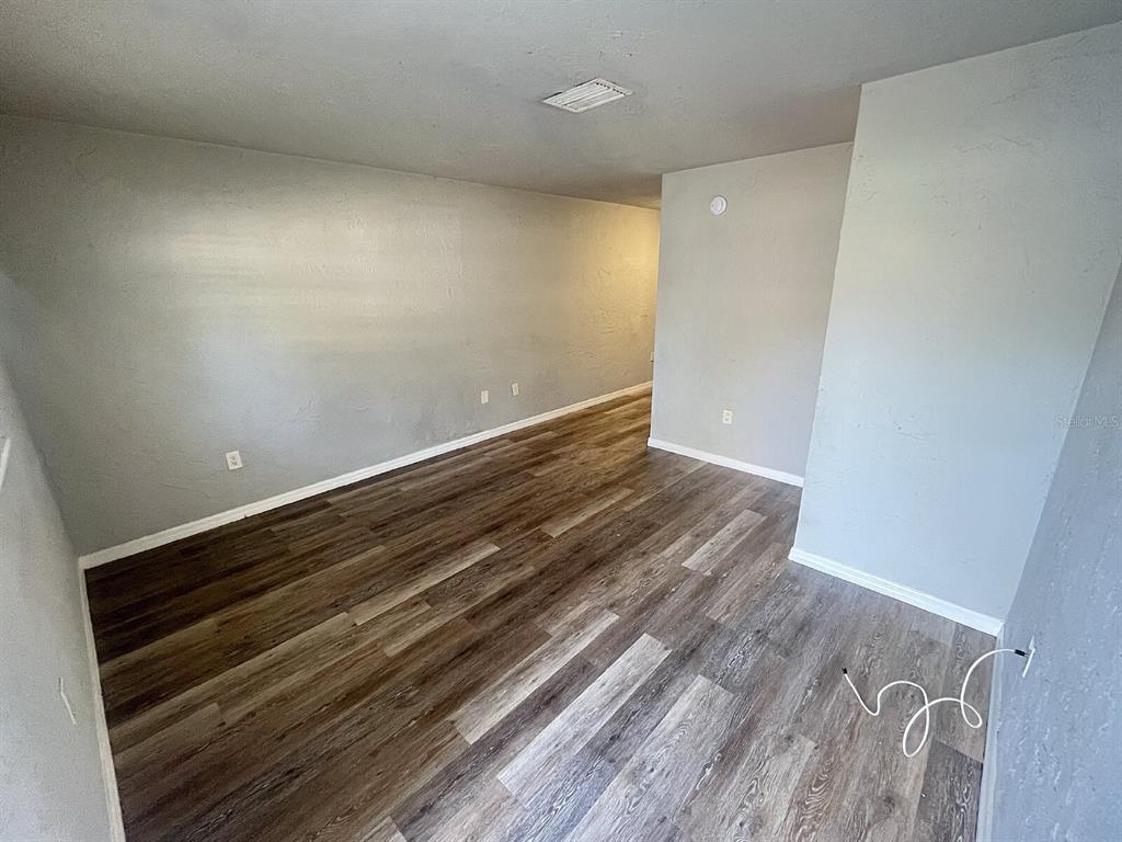 An empty room features gray walls, wood-look flooring, and a white ceiling vent — 2519 9TH AVENUE W UNIT 2, BRADENTON, FL