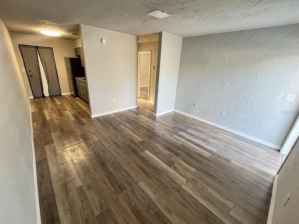 An interior view shows an open-concept living area with wood-look flooring and a kitchen beyond — 2519 9TH AVENUE W UNIT 2, BRADENTON, FL