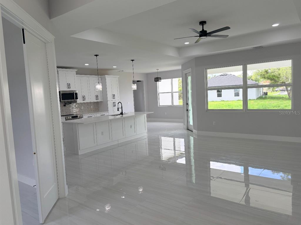 A bright, open-concept kitchen and living area features white cabinetry, a large island, and tile flooring — 1393 RICHMAR STREET, NORTH PORT, FL