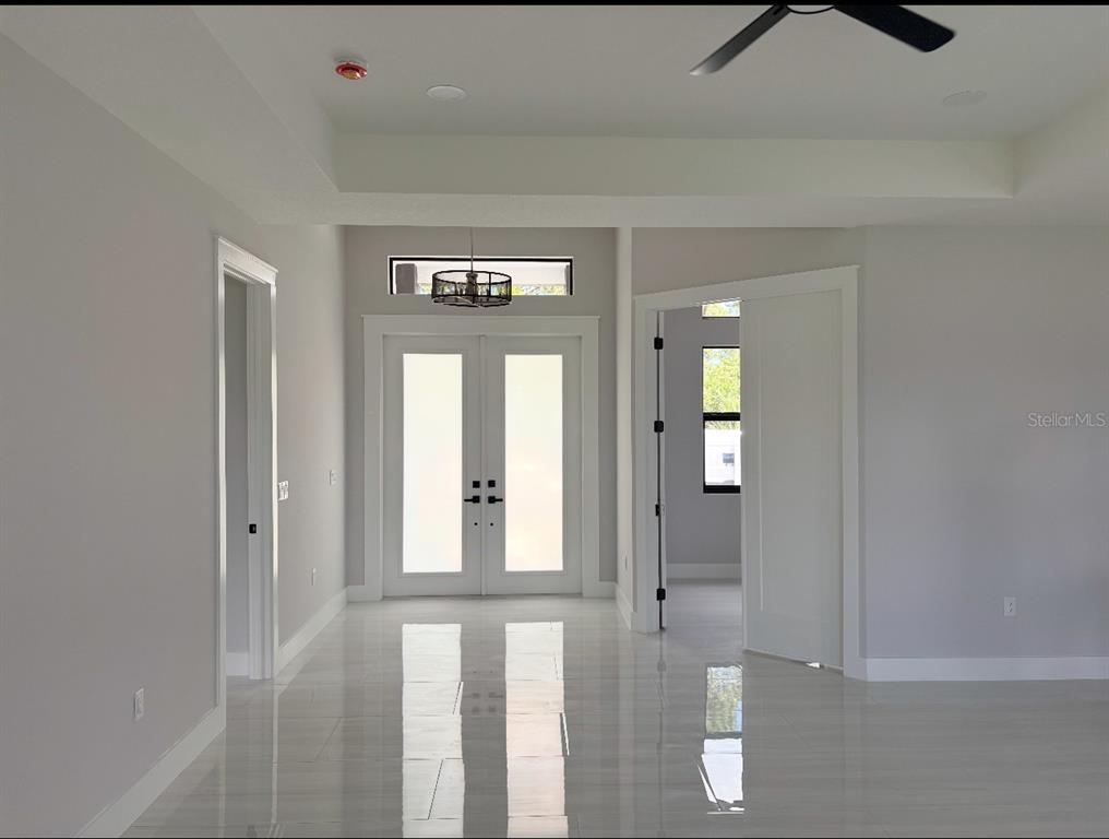 A bright entryway features double glass doors, a tray ceiling, and polished tile flooring — 1393 RICHMAR STREET, NORTH PORT, FL
