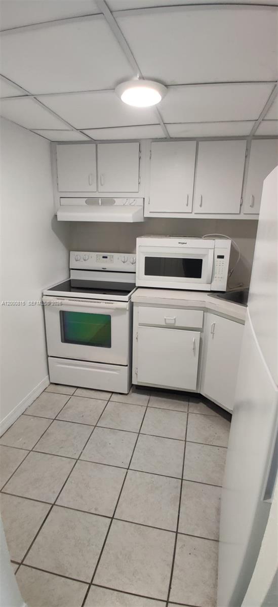 A small kitchen features white cabinets, a white stove, a microwave, and tiled flooring — 4550 NW 9th St # 706E, Miami FL 33126, MIAMI, FL