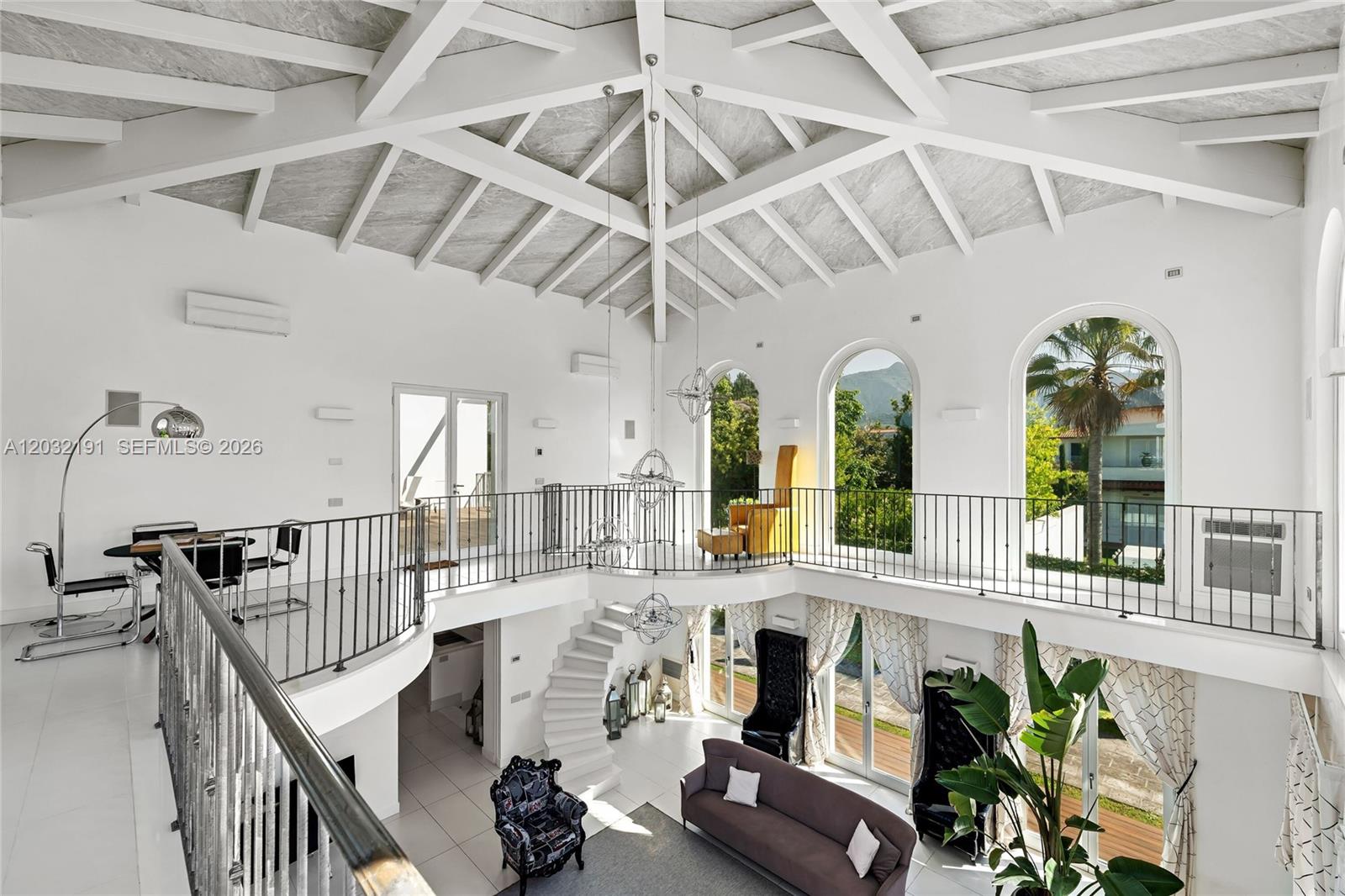 A two-story living area features a vaulted ceiling, white tile floors, and a curved balcony — Luxury Real Estate Forte Dei Marmi Max Mlekus, FL