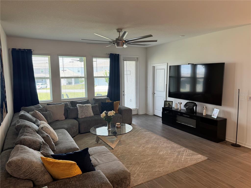 A living room features a large gray sectional sofa, a glass coffee table, and a television — 2844 ARMSTRONG AVENUE, CLERMONT, FL
