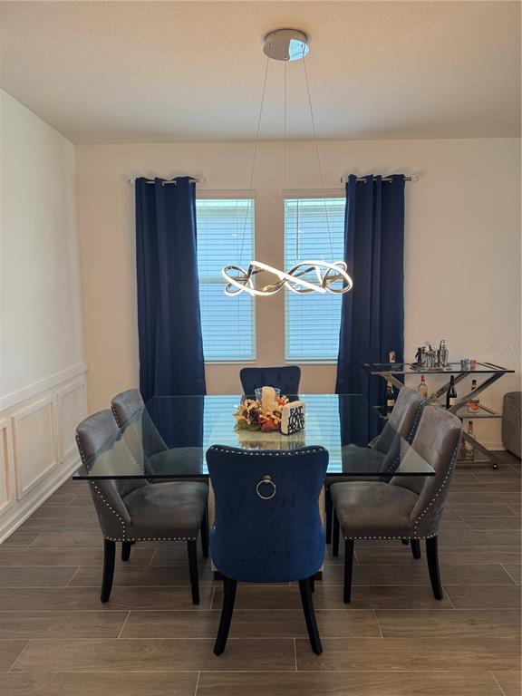 A dining room features a glass-topped table, gray and blue chairs, and a modern light fixture — 2844 ARMSTRONG AVENUE, CLERMONT, FL