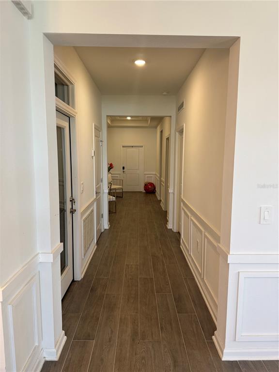 A long hallway features wood-look tile flooring, white wainscoting, and multiple interior doors — 2844 ARMSTRONG AVENUE, CLERMONT, FL