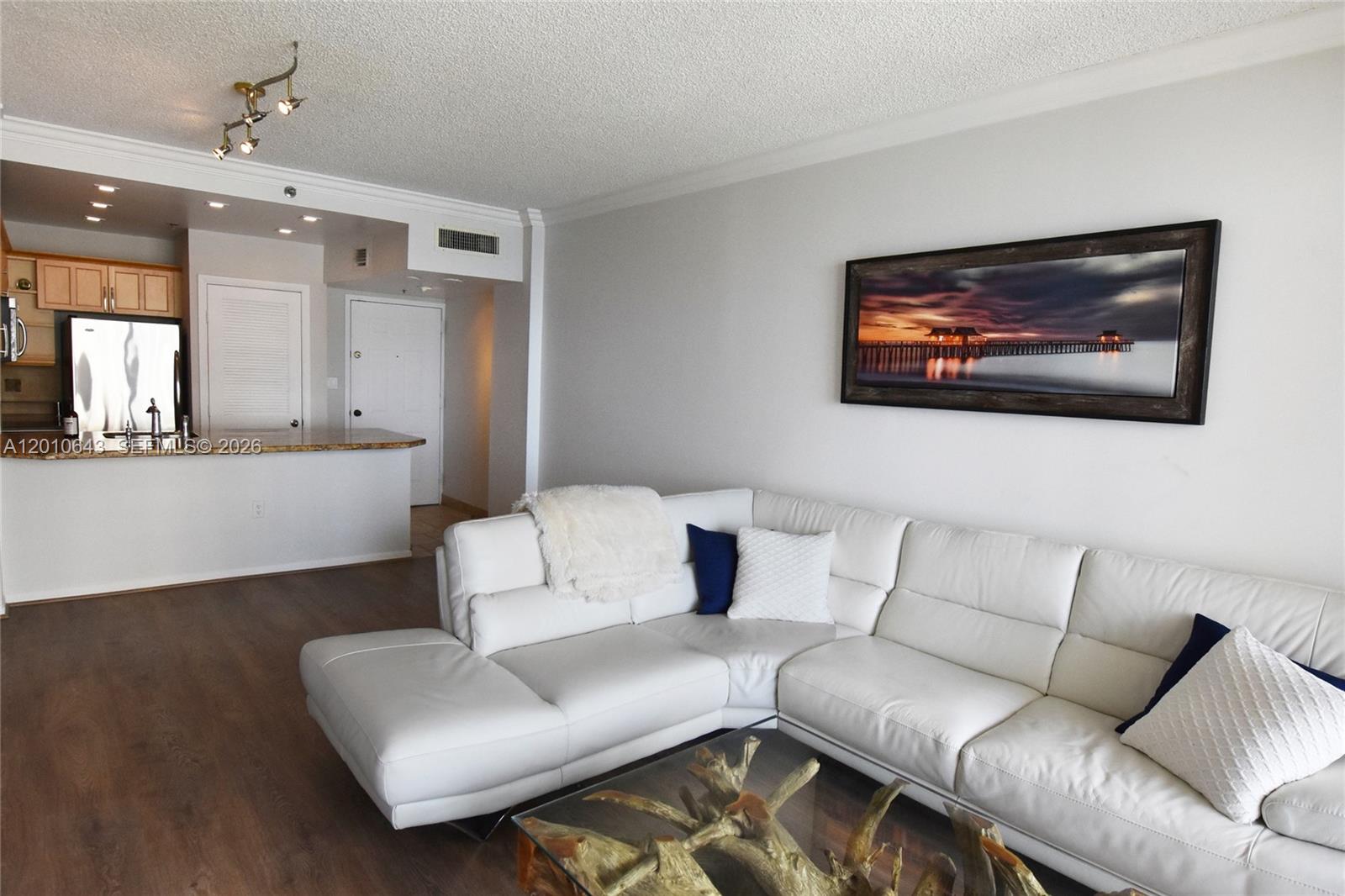 A living room features a white sectional sofa, a glass coffee table, and a kitchen area — 540 Brickell Key Dr, Miami FL 33131, MIAMI, FL