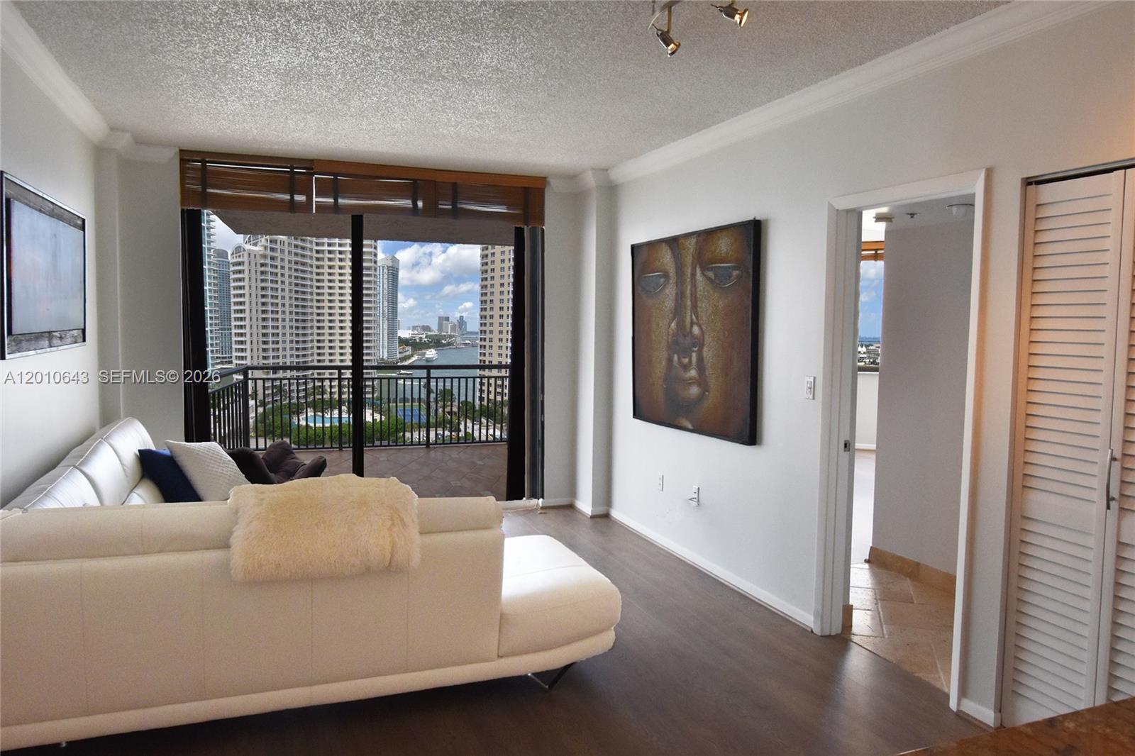 A living room features a white sectional sofa, a large Buddha painting, and a balcony view — 540 Brickell Key Dr, Miami FL 33131, MIAMI, FL