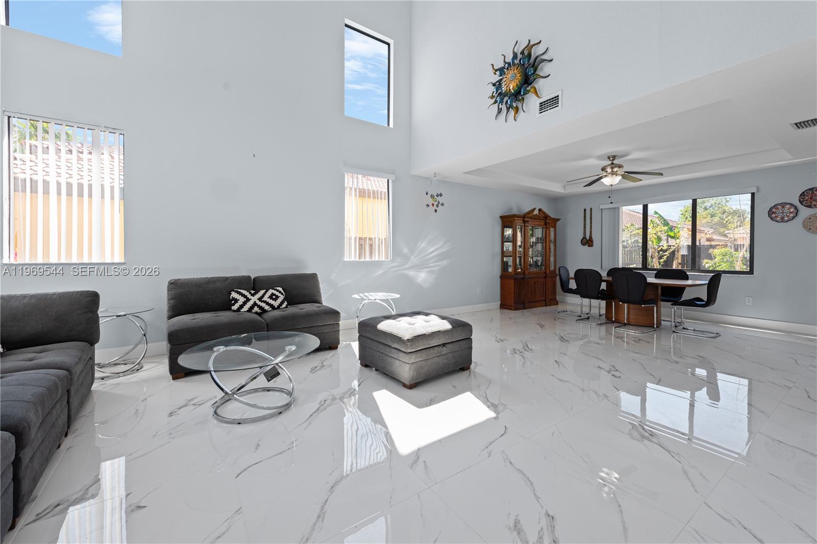A living and dining area features high ceilings, white marble floors, and large windows — 972 NE 36th Ave, Homestead FL 33033, HOMESTEAD, FL