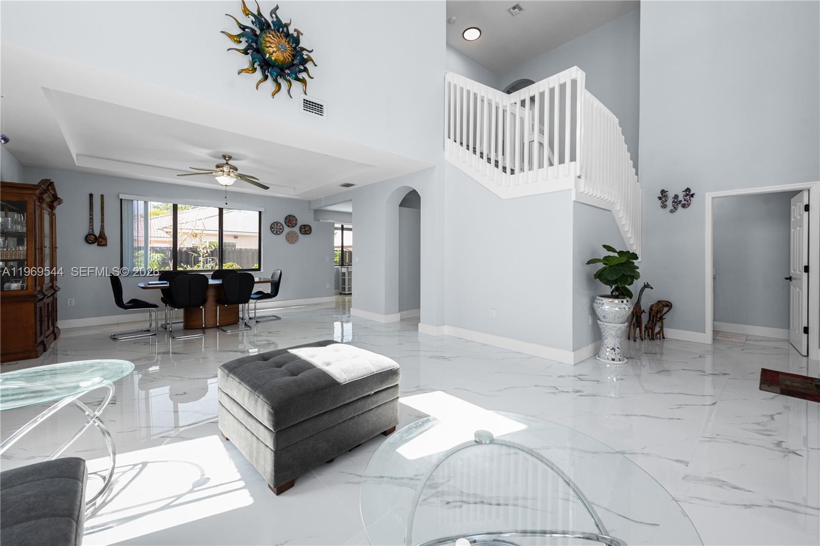 A spacious living and dining area features white marble floors, a staircase, and high ceilings — 972 NE 36th Ave, Homestead FL 33033, HOMESTEAD, FL