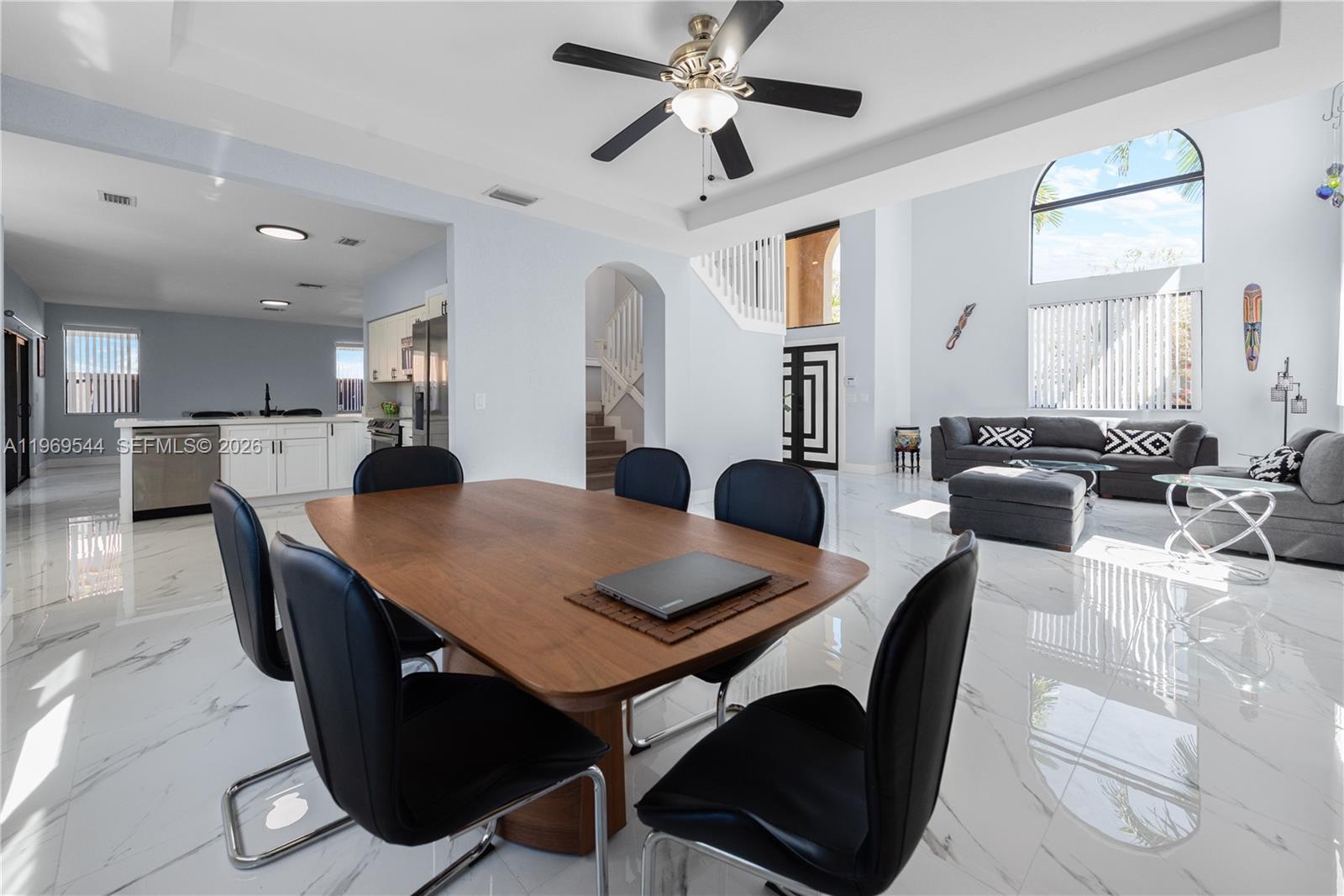 A dining area with a wooden table and black chairs sits before an open living room — 972 NE 36th Ave, Homestead FL 33033, HOMESTEAD, FL