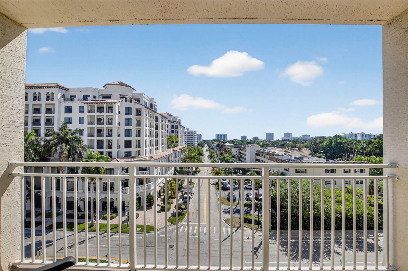 A view from a balcony overlooking a street, palm trees, and surrounding apartment buildings — 99 SE Mizner Boulevard # 603, Boca Raton FL 33432, BOCA RATON, FL