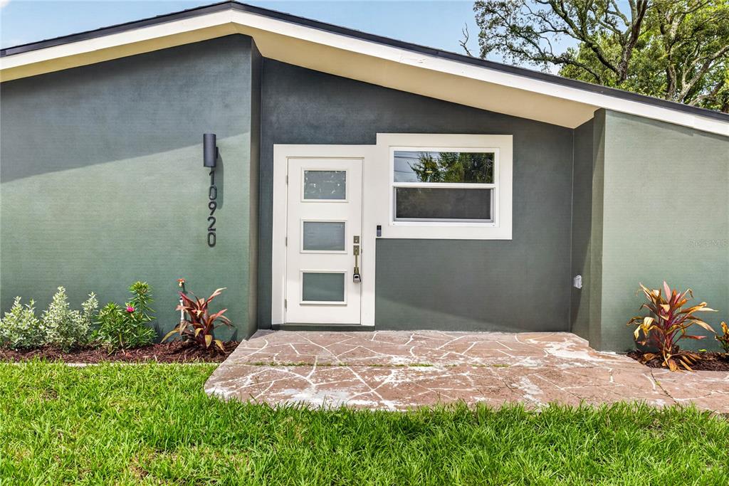 A modern front entrance features a white door with three glass panels and stone paving — 10920 N 14TH STREET, TAMPA, FL