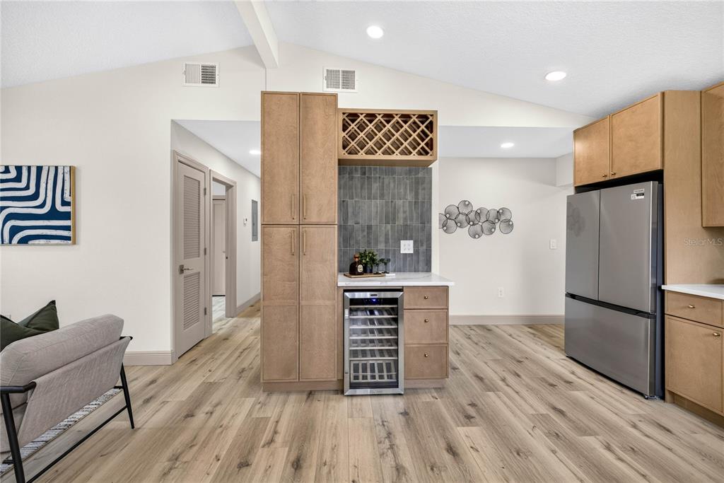 A kitchen features light wood cabinets, a wine cooler, and a gray tiled backsplash — 10920 N 14TH STREET, TAMPA, FL