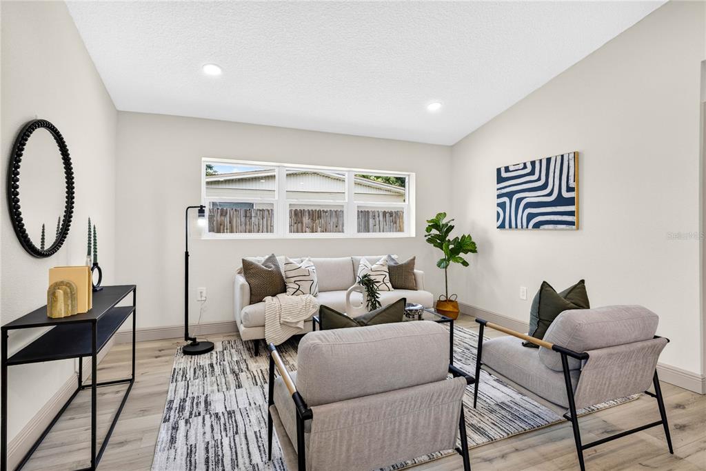 A living room features light wood flooring, a sofa, two armchairs, and a black console table — 10920 N 14TH STREET, TAMPA, FL