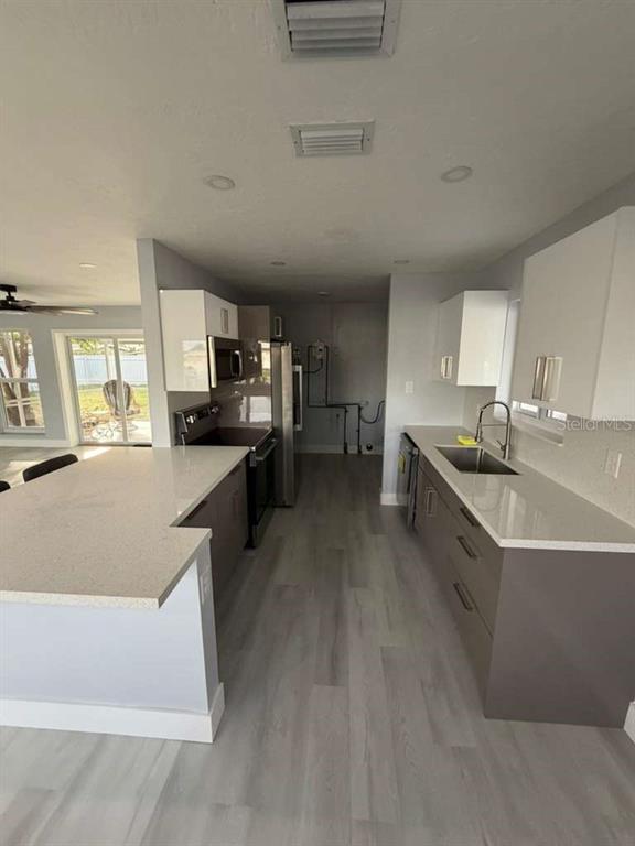 A modern kitchen features white upper cabinets, gray lower cabinets, and a large quartz island — 22202 BELINDA AVENUE, PORT CHARLOTTE, FL