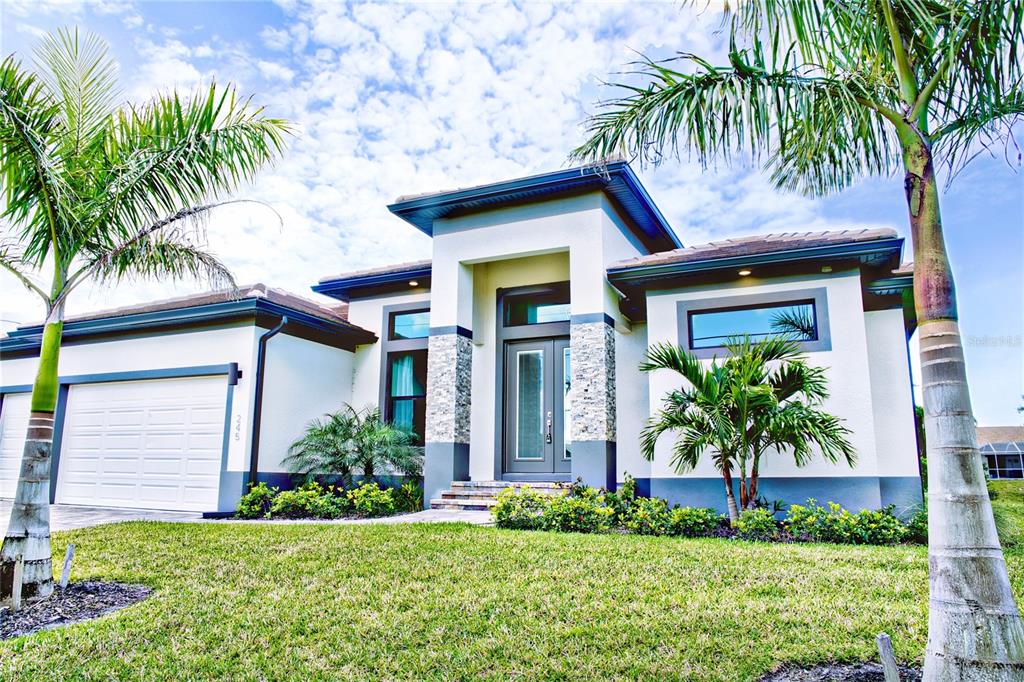A modern single-story house with a white stucco facade, stone accents, and two palm trees — 245 MARKER ROAD, ROTONDA WEST, FL