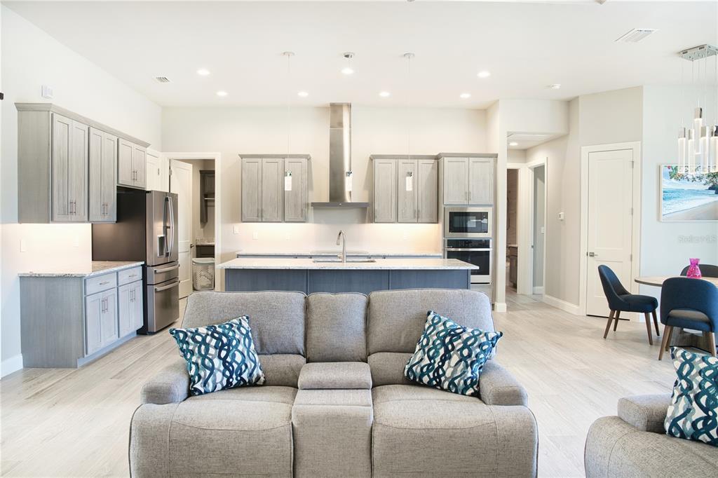 A modern kitchen with gray cabinets and a central island overlooks a gray sofa — 245 MARKER ROAD, ROTONDA WEST, FL