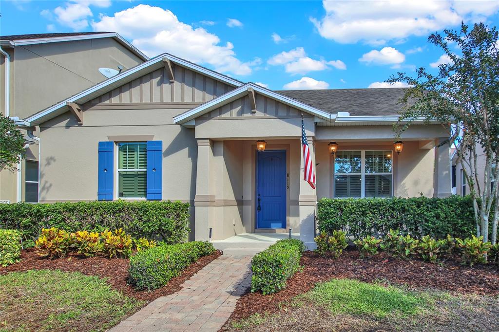 A beige single-story house features a blue front door, blue shutters, and a brick walkway — 8119 LAUGHING GULL STREET, WINTER GARDEN, FL