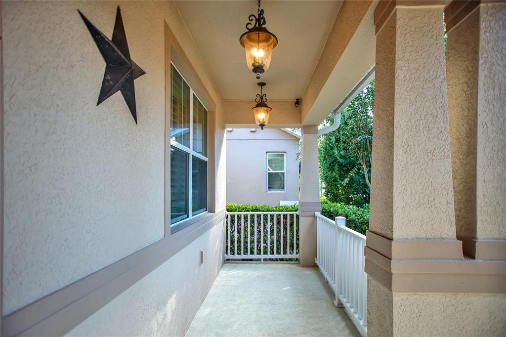 A covered porch features a concrete floor, white railings, two hanging lanterns, and a wall star — 8119 LAUGHING GULL STREET, WINTER GARDEN, FL