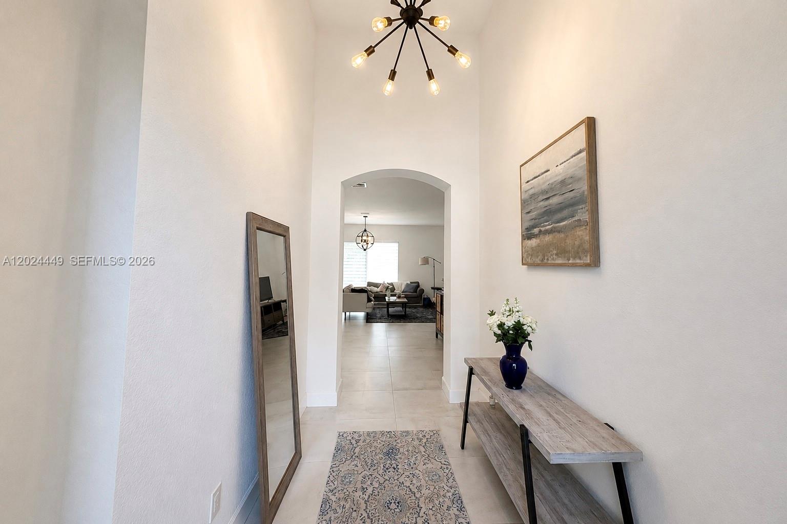 A bright entryway features a tall arched opening, a console table, and a modern chandelier — 4486 W Whitewater Ave, Weston FL 33332, WESTON, FL