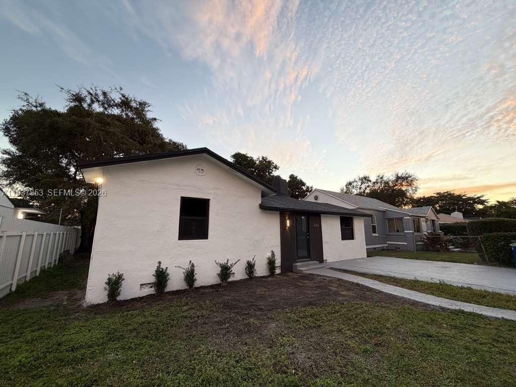 A white, single-story house with a dark roof and trim sits on a grassy lot — 854 NW 76th St, Miami FL 33150, MIAMI, FL