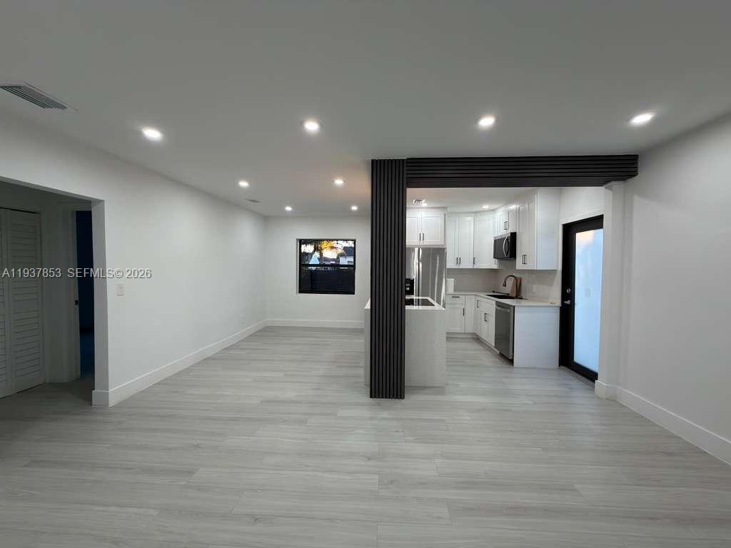 A modern open-concept kitchen and living area features light wood flooring and recessed lighting — 854 NW 76th St, Miami FL 33150, MIAMI, FL