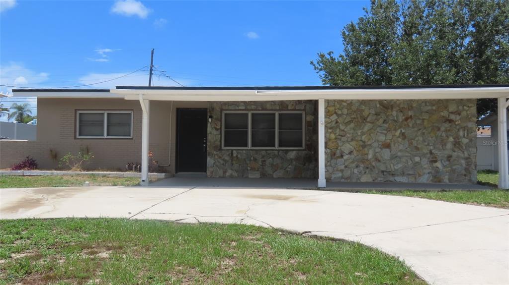 A single-story house features a stone facade, a covered porch, and a concrete driveway — 12208 105TH STREET, LARGO, FL
