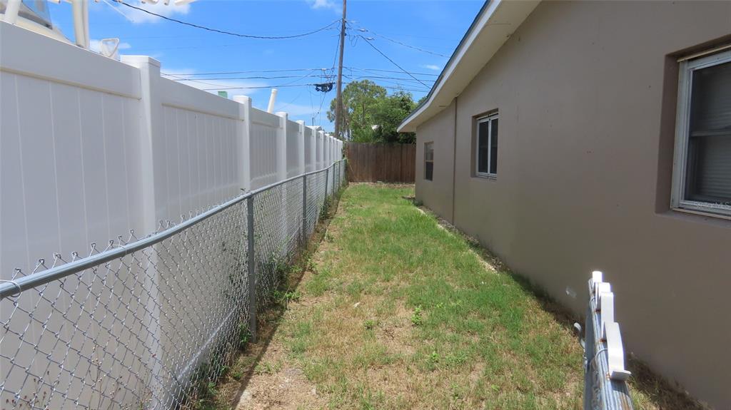 A narrow side yard features a chain-link fence, a white privacy fence, and a house — 12208 105TH STREET, LARGO, FL