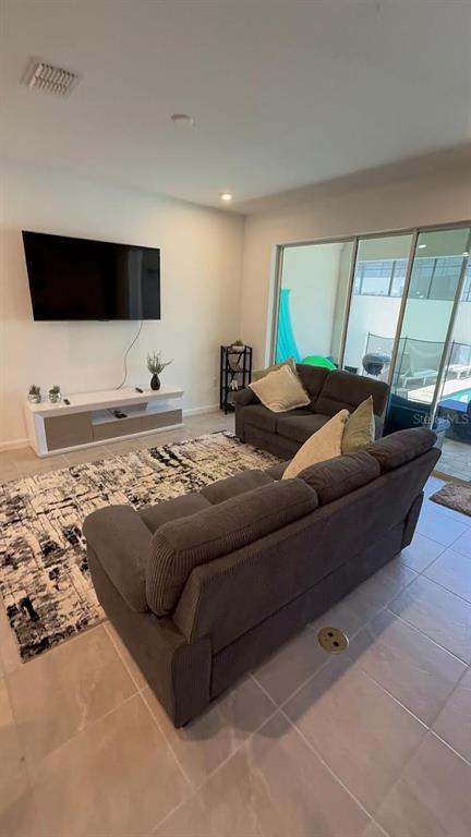 A living room features a wall-mounted television, a media console, and two gray sofas — 2334 ZABALLINA PLACE UNIT 2343, KISSIMMEE, FL
